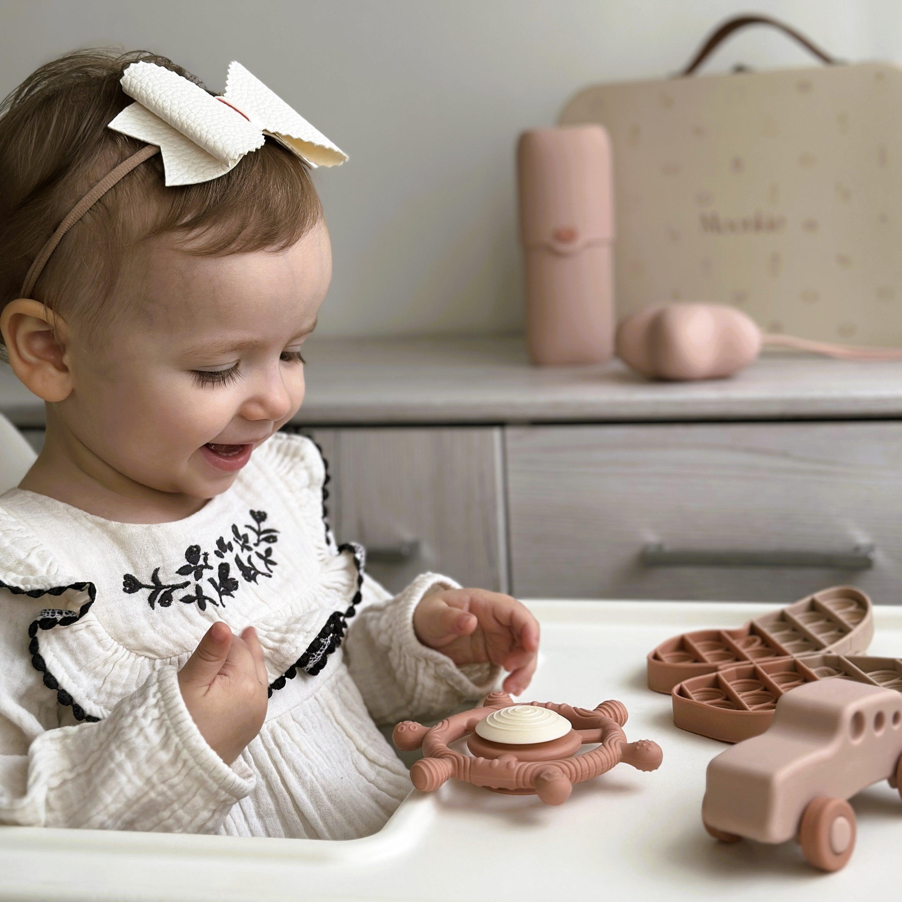A baby is playing Moonkie's On-The_Go gift set.
