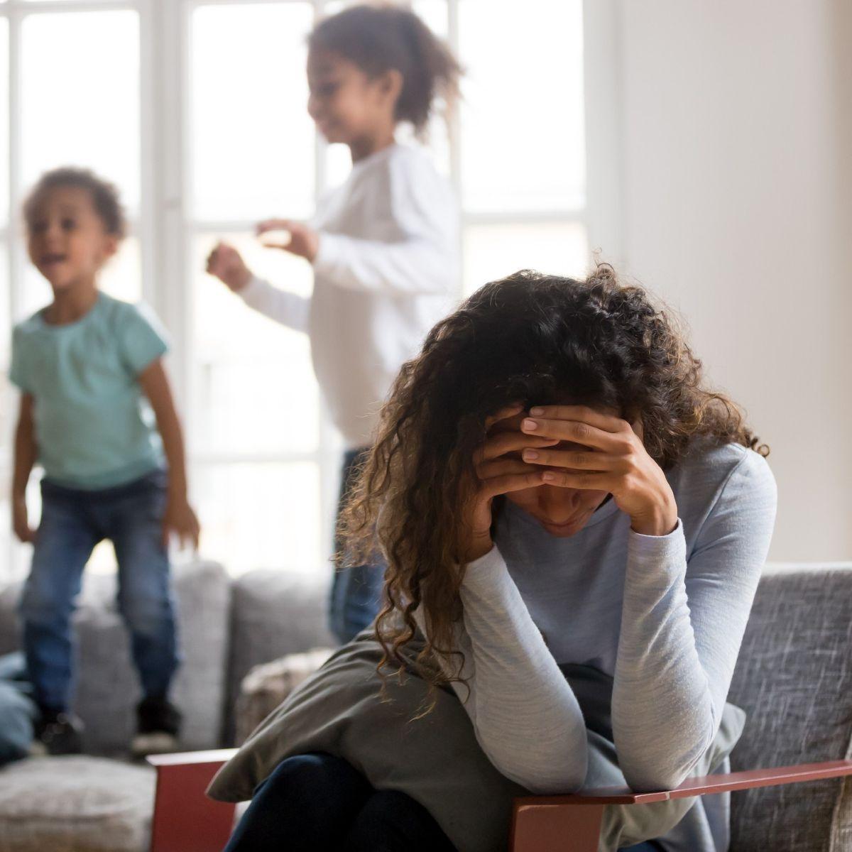 Sad mother and playful children at home