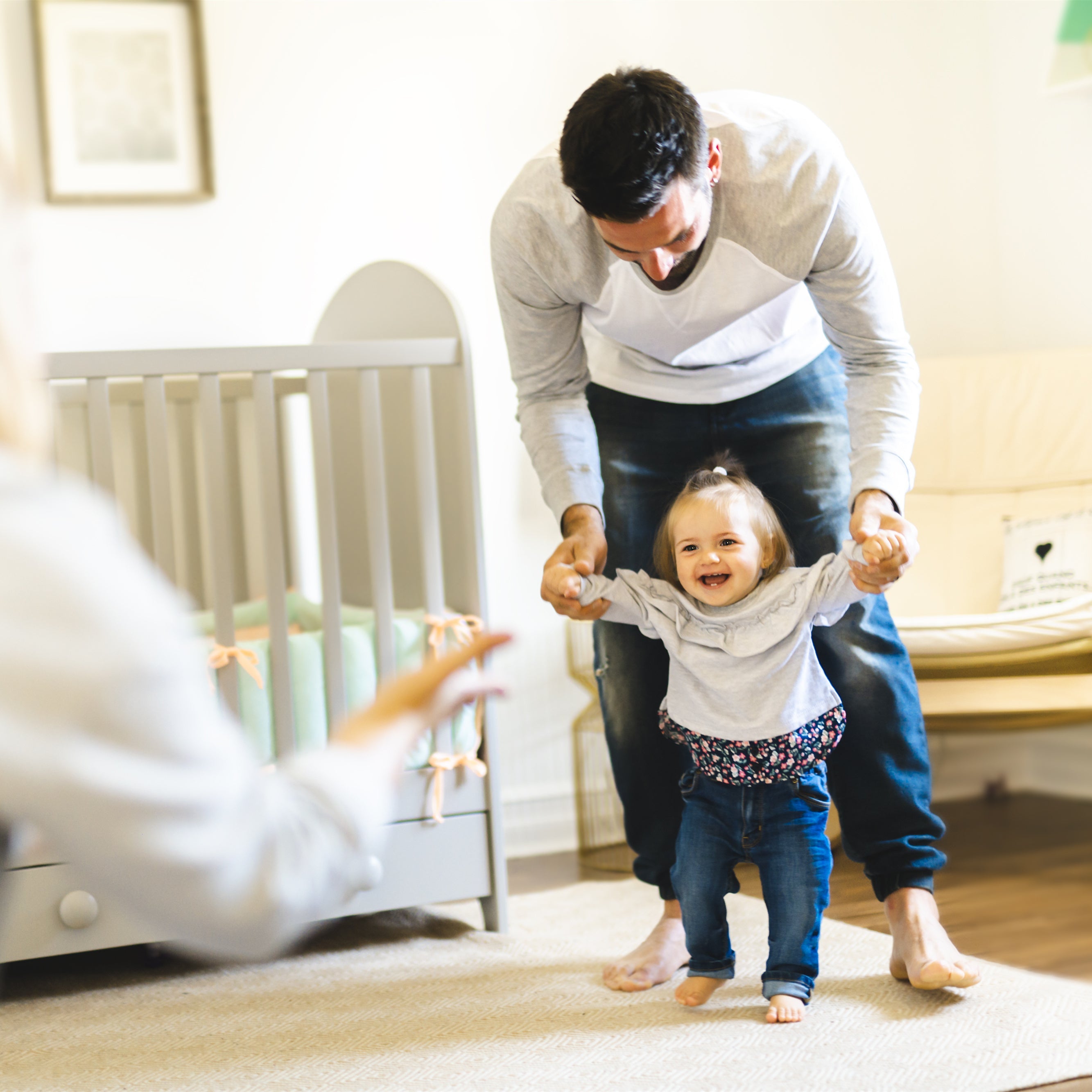 Little baby girl first steps with the help of parent