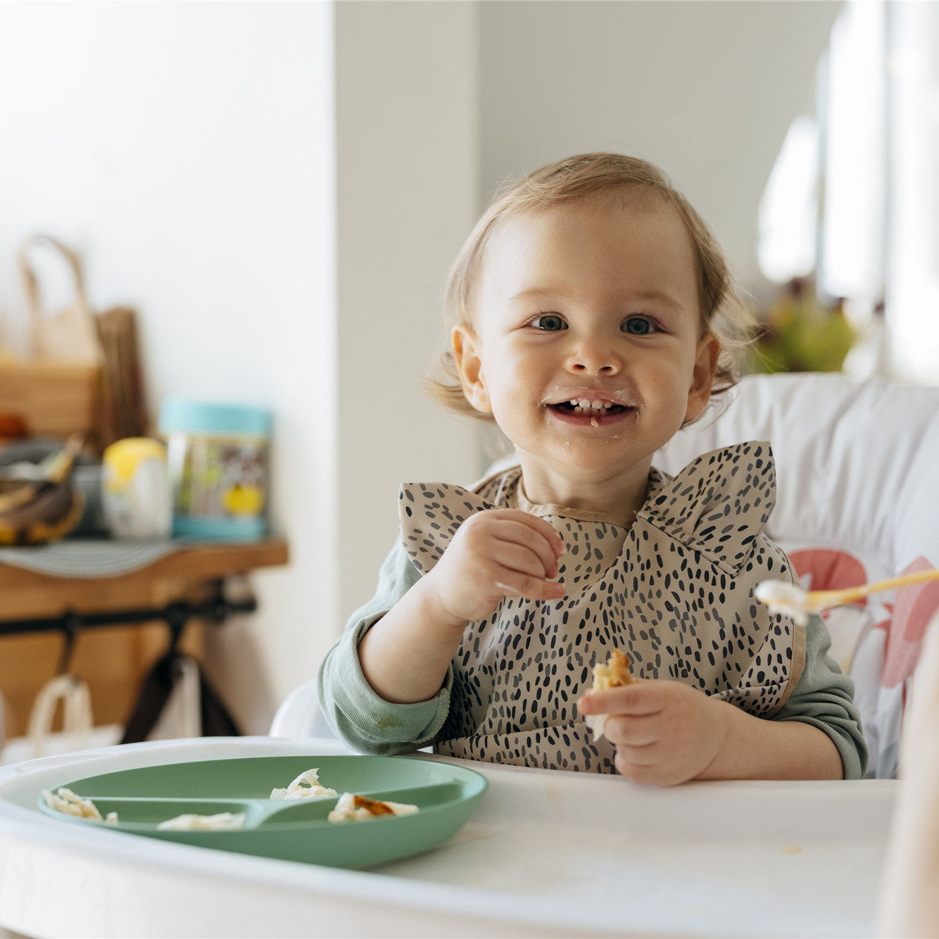 Cheerful baby girl eating meal with mother