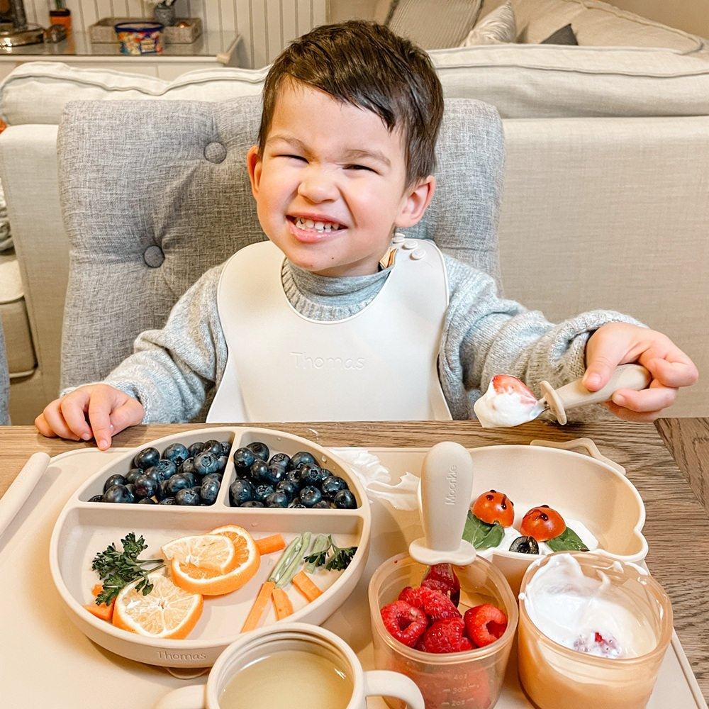 A toddler is using Moonkie feeding set