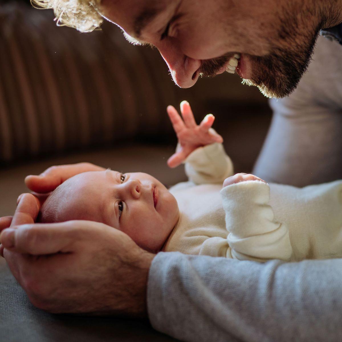 A loving dad gently plays with his baby.