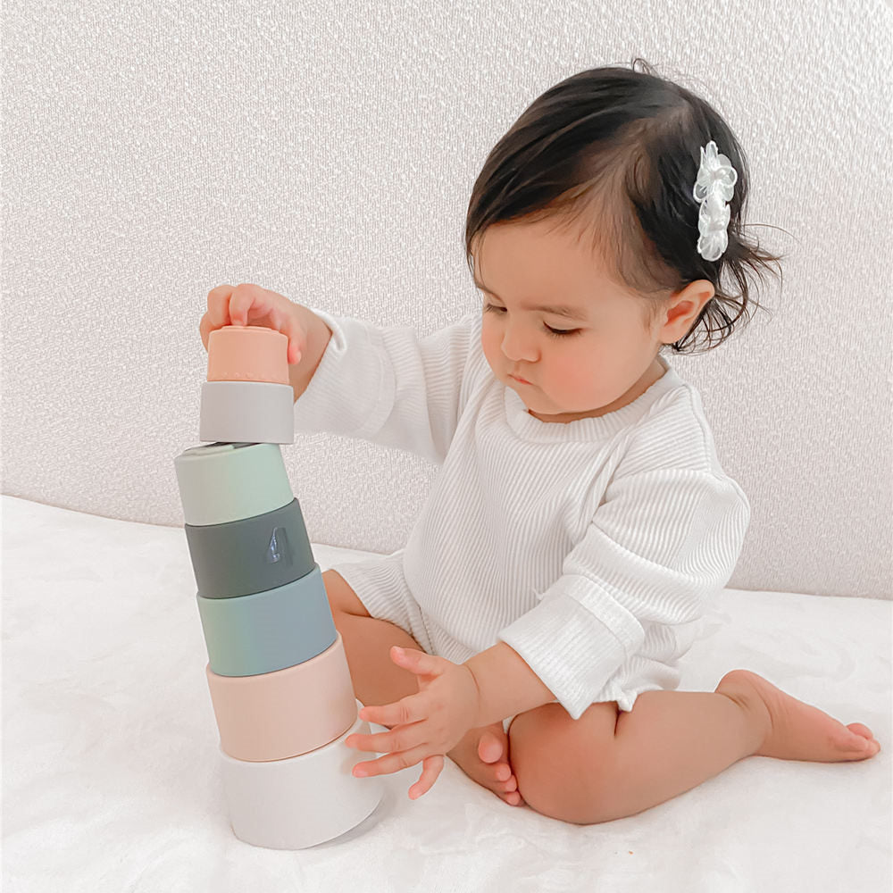 A baby girl is playing Moonkie stacking toy