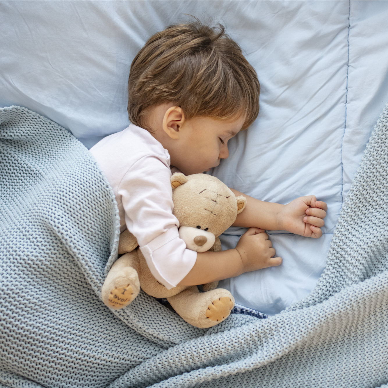 Boy sleeping on bed with teddy bear
