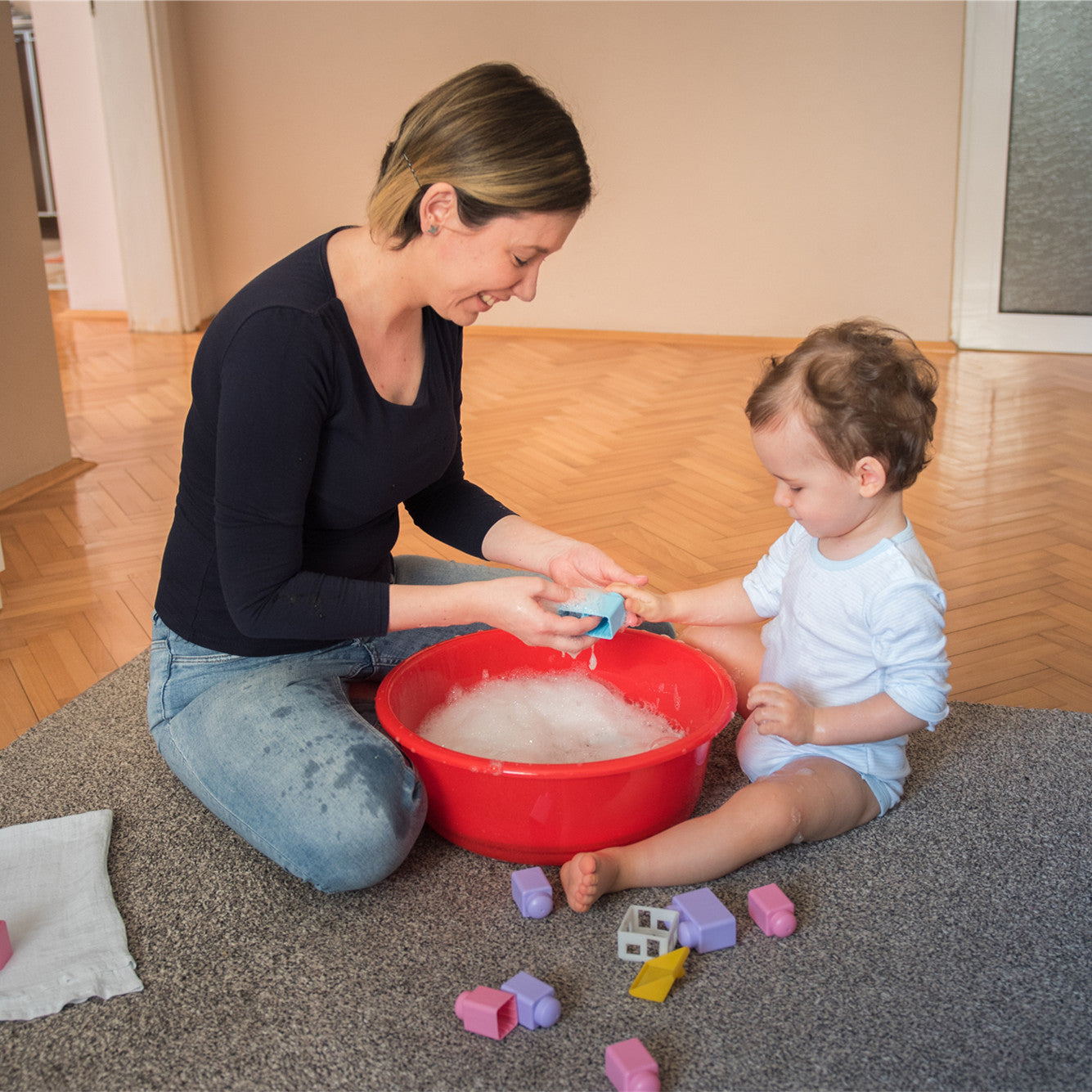 Mother and son playfully washing toys together in a living room