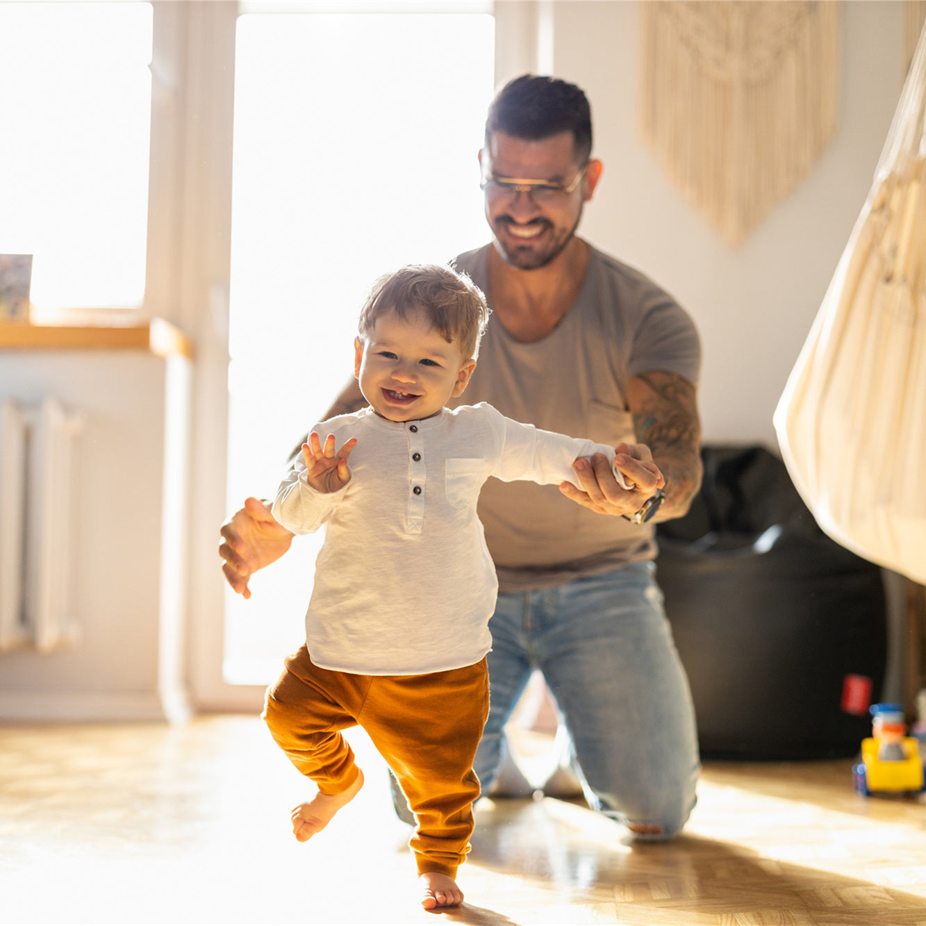 Happy father helping little son walking in living room