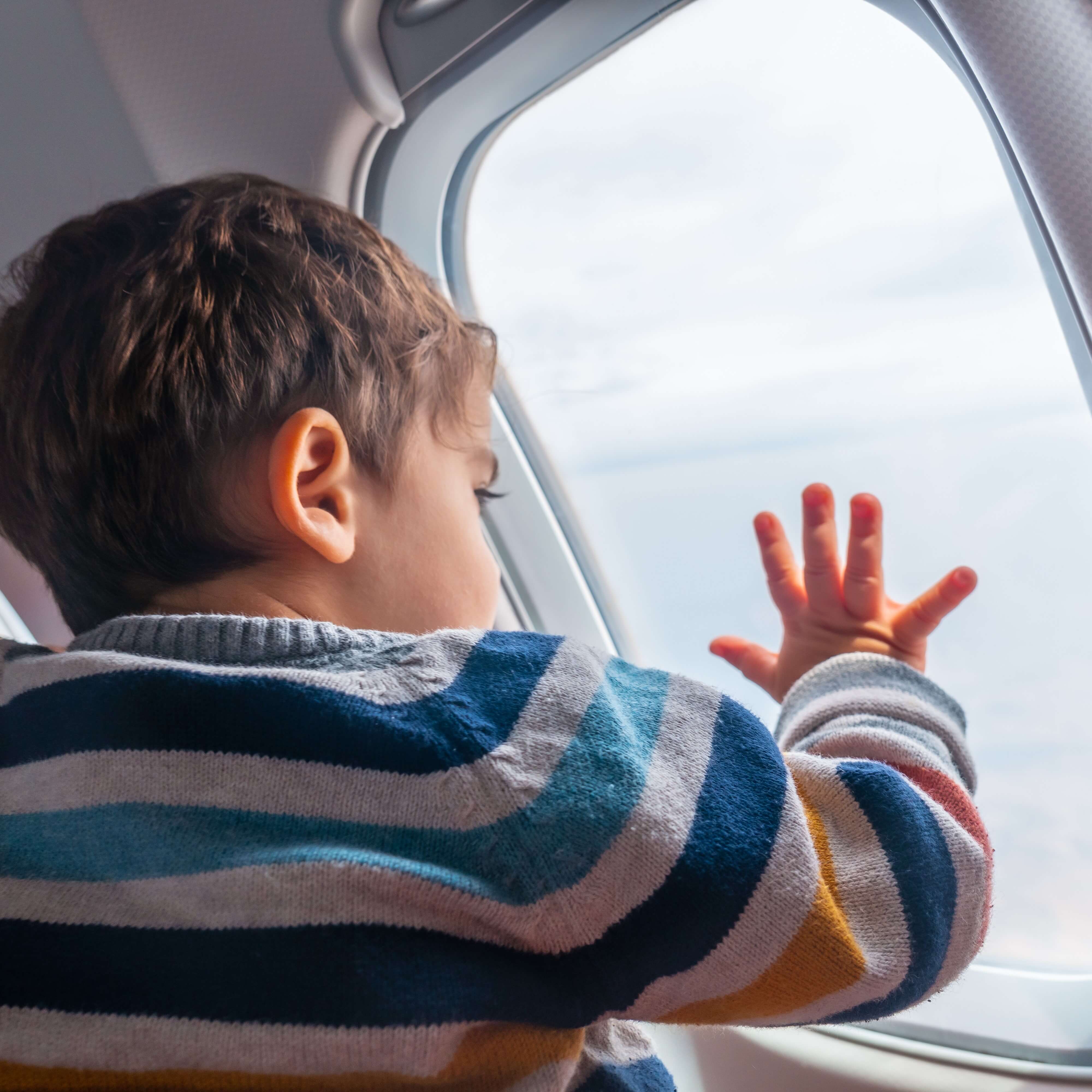 Boy traveling by plane on vacation looking out the window.