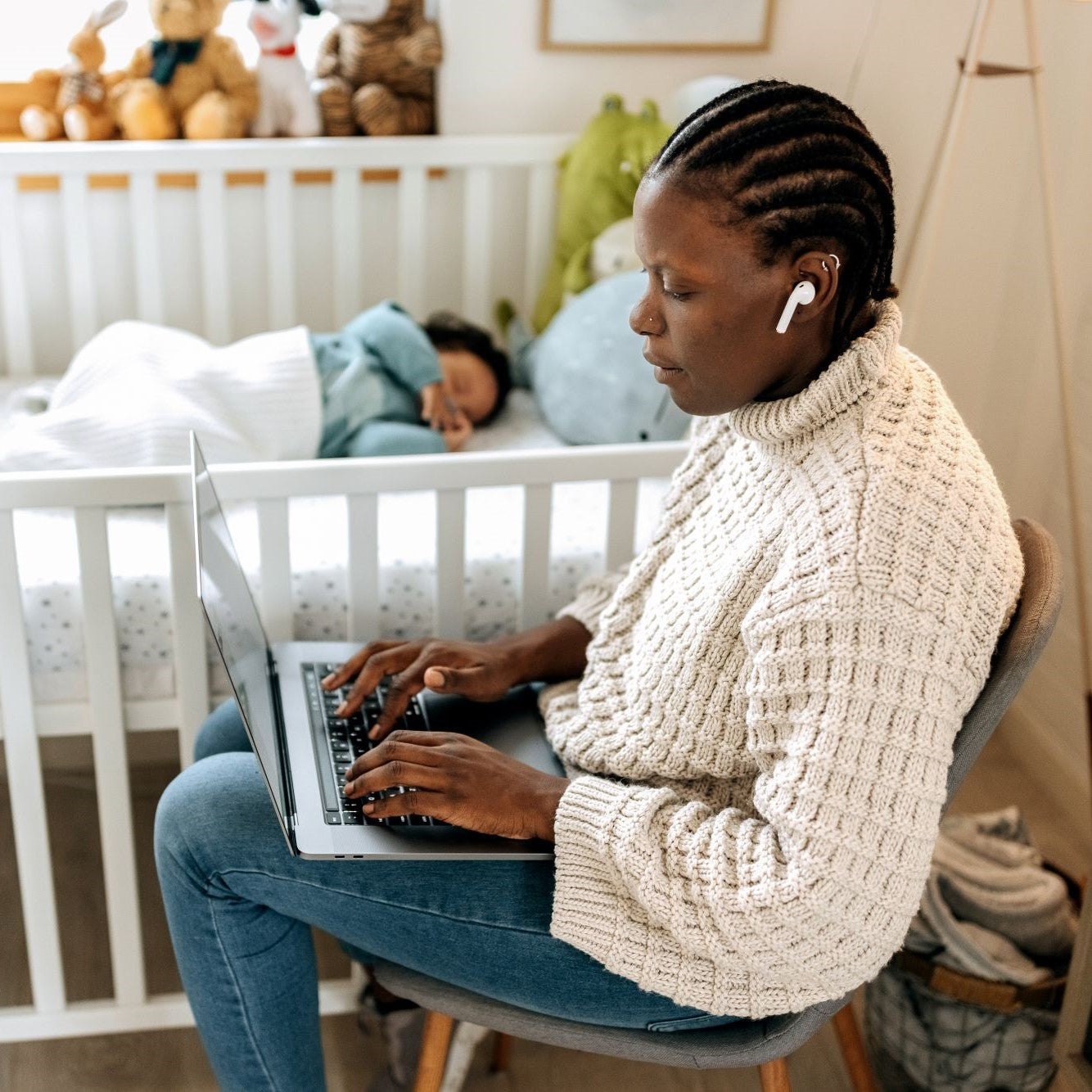 Working mother using laptop next to her sleeping baby