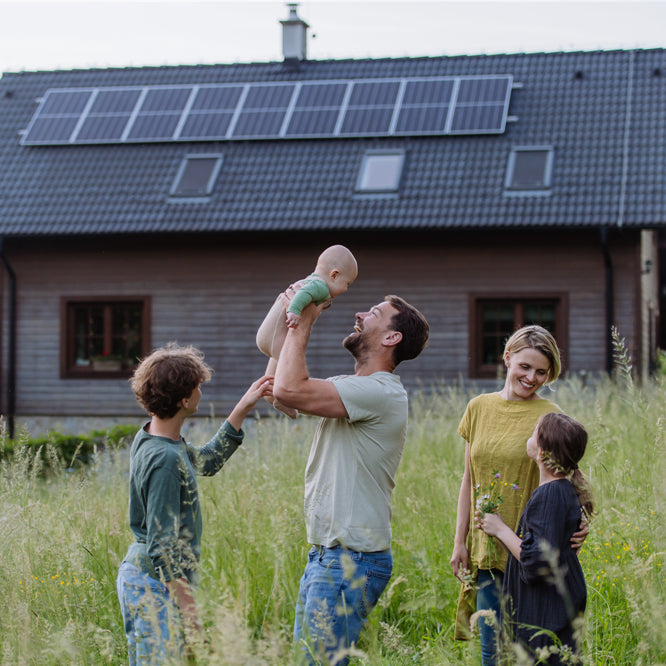 Happy family near their house with solar panels