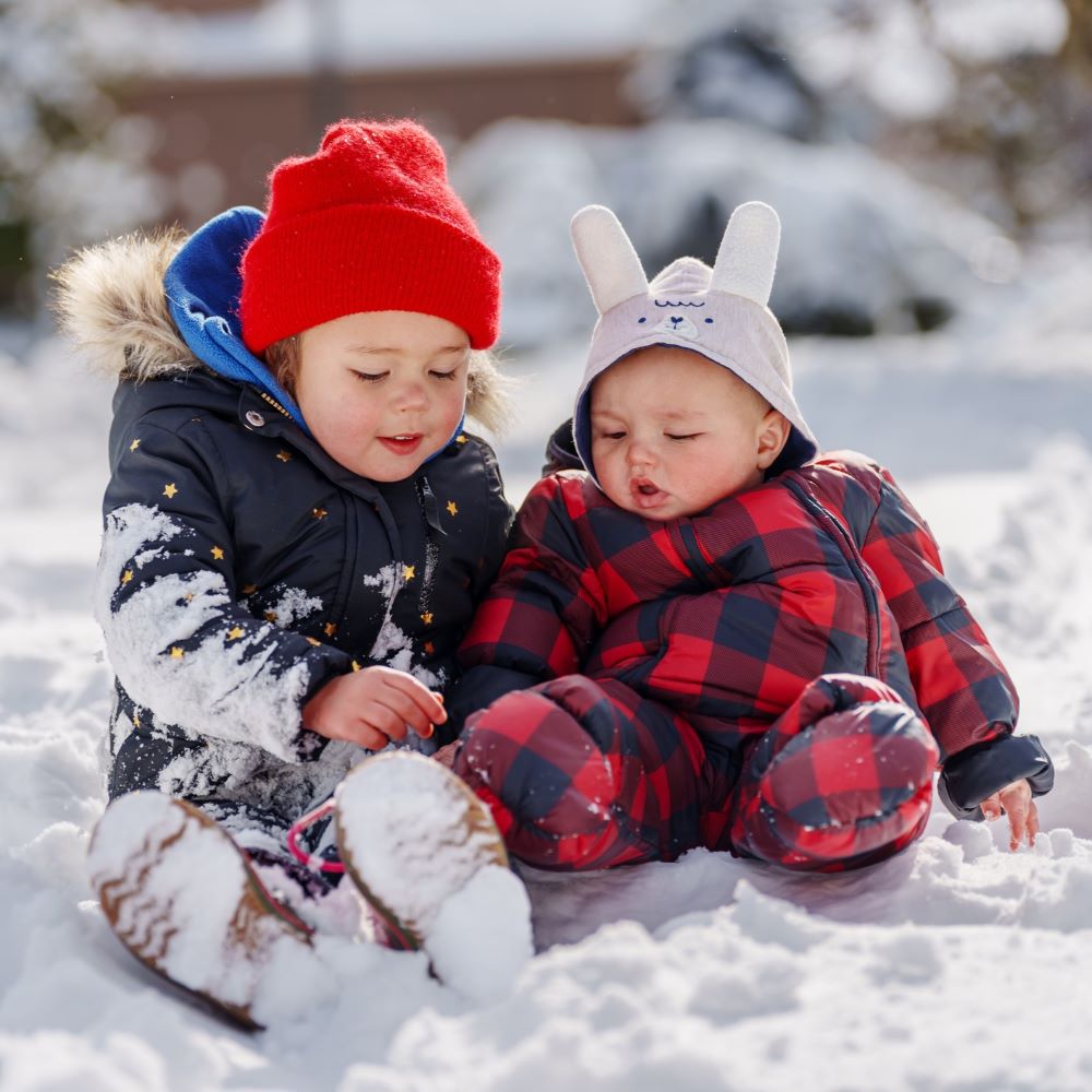 Young brother and sister play in the snow together