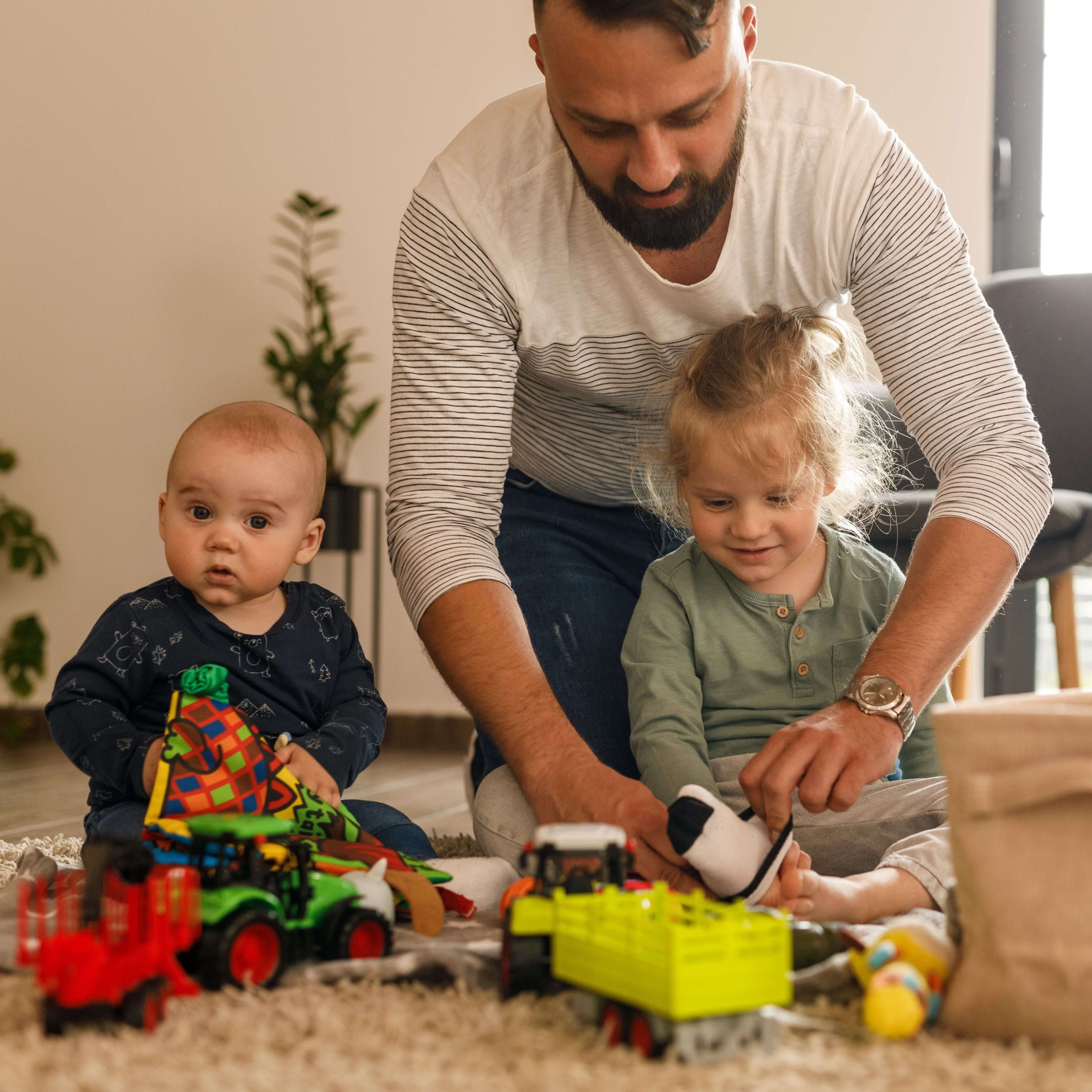 Father is putting socks on his toddler son's feet while he is playing