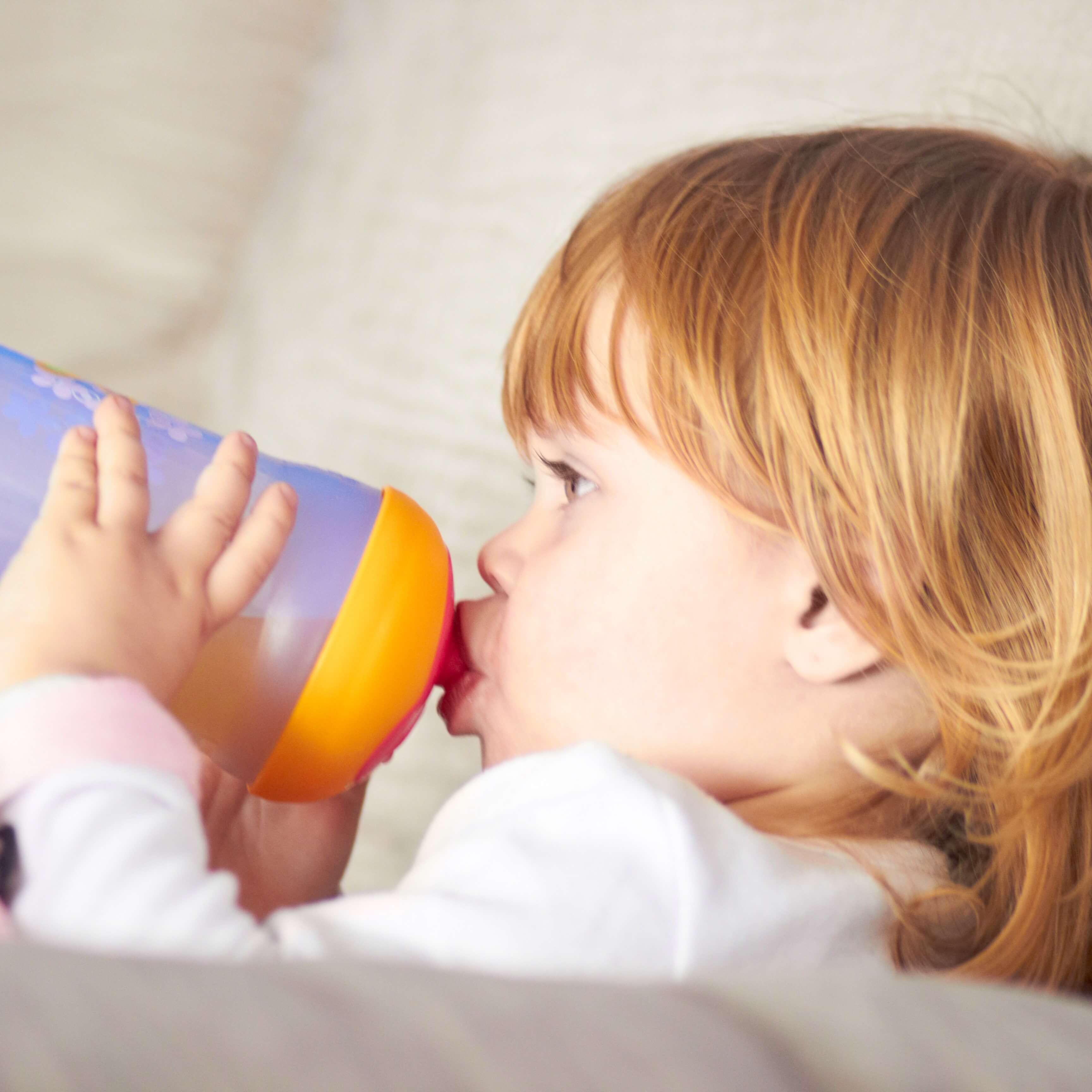 A baby girl is drinking with a sippy cup