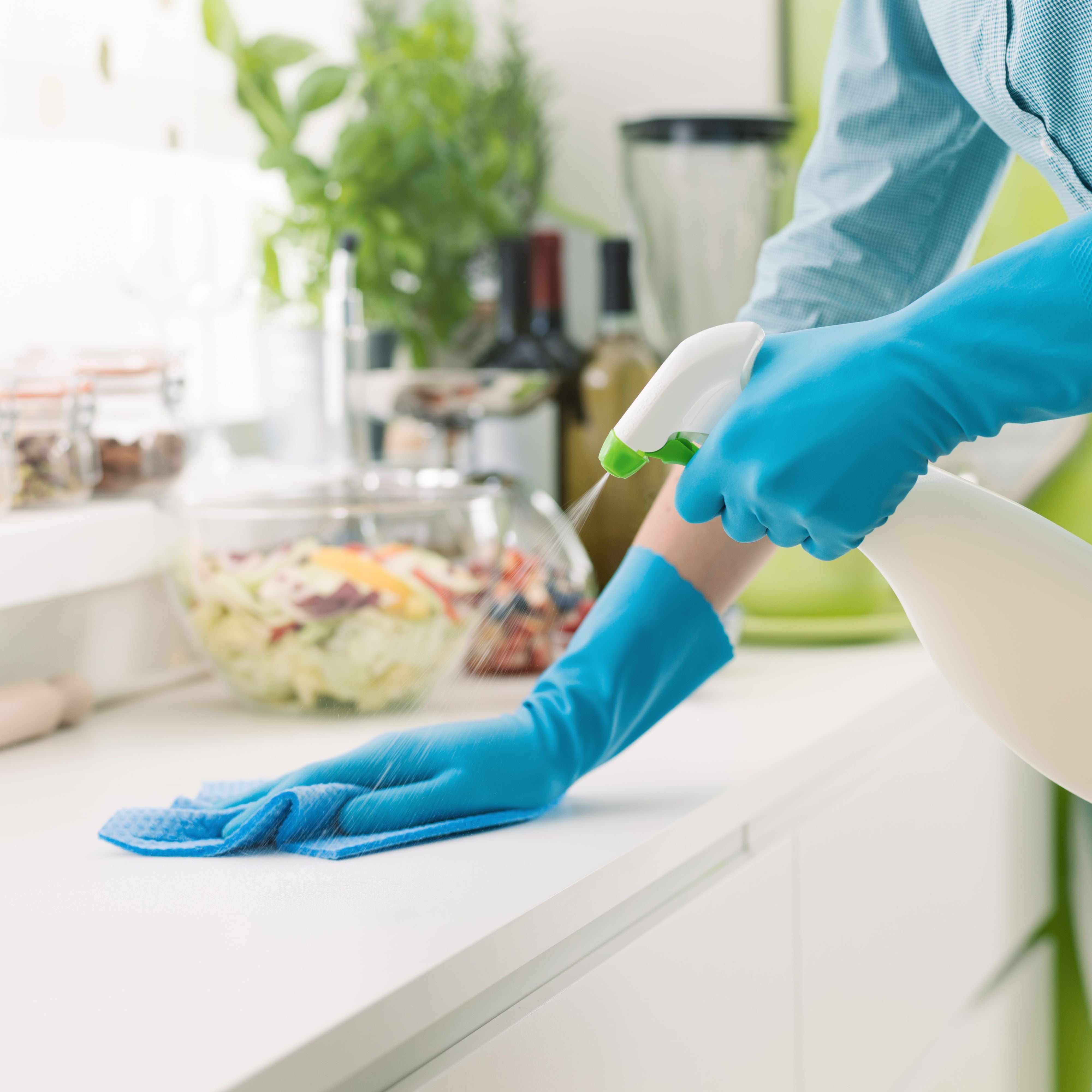 A woman is cleaning with a spray detergent.