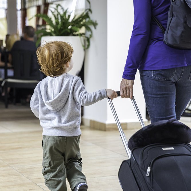 Mother or Grand Mother and Baby Boy walking in the airport with Suitcase