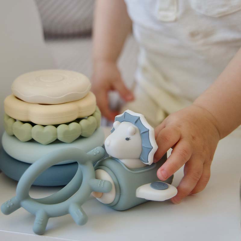 A baby is playing Moonkie's dino stacking teether rings