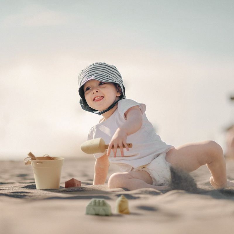 Baby playing in the sand with beach toys