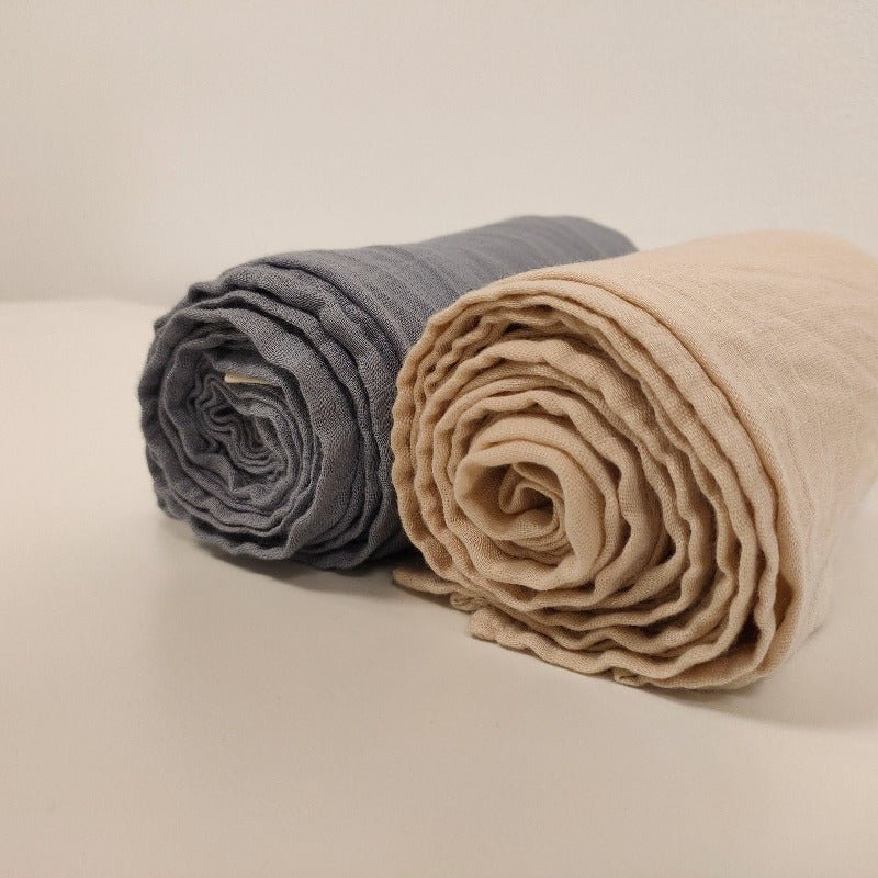 Two rolled-up cloths, one gray and one beige, on a light surface.